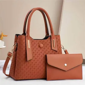 Detailed view of brick red embossed tote bag with matching envelope clutch and gold hardware