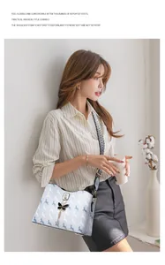 Détail du sac seau imprimé avec charm papillon en métal et bandoulière rayée