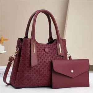 Burgundy embossed woven handbag set with gold hardware and adjustable strap in studio
