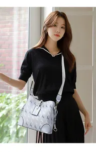 Detail of grey-blue bucket bag with deer print on a female model by the window