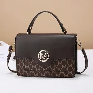 Deep brown monogram crossbody bag with gold M logo buckle and adjustable strap