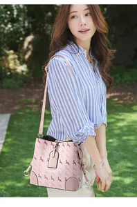 Pink bucket bag with red deer prints and gold buckles shown in a garden setting