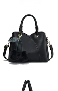 Front view of black pebbled leather handbag with plush cherry charm and gold hardware
