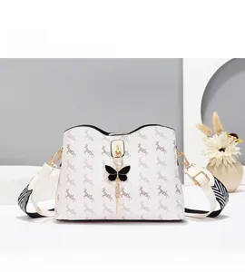 Détail d'un sac seau beige avec imprimés cerf, breloque papillon et bandoulière rayée