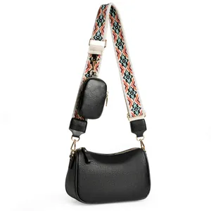 Detail of black saddle bag with textured leather, wide ethnic strap and round coin purse