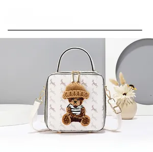 Detail of white square crossbody bag with teddy bear patch and patterned texture
