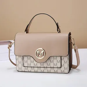 Detail of beige flap bag with gold M-logo buckle and adjustable crossbody strap