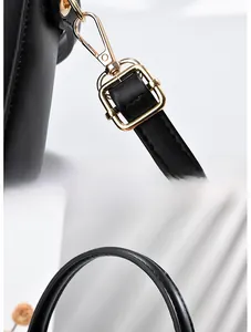 Dettagli dei moschettoni dorati e della ferramenta sulla borsa minimalista in pelle nera