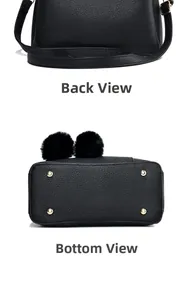 Detail view of black pebble leather handbag featuring protective gold metal feet and pompom