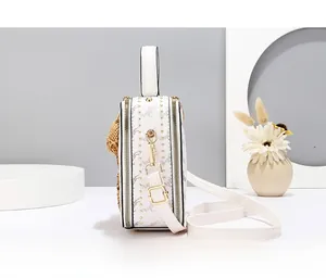 Detailed side view of white box bag with horse print, gold studs and bear charm