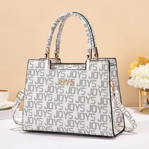 Détail du sac à main blanc à texture crocodile avec logo doré et motifs de lettres JOYS