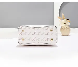 Vue détaillée de la base du sac seau montrant les clous dorés et les motifs imprimés chic
