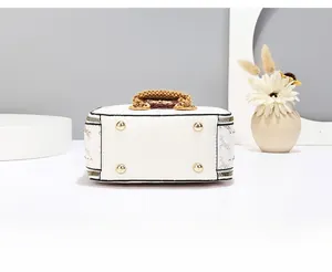 Detail view of the white handbag base with four protective gold-tone metal feet