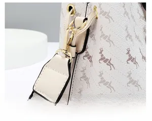 Detail view of gold detachable lobster clasp on a textured bucket bag with deer pattern