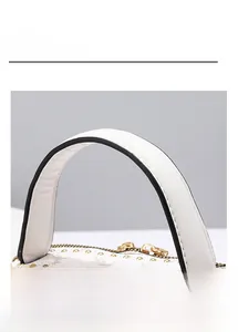 Close-up of white leather handbag with retro pattern, gold rivets, and top zipper