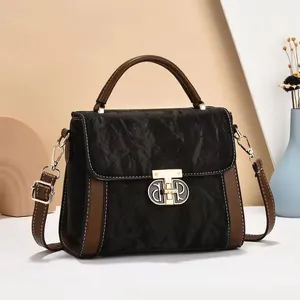 Chic black pleated shoulder bag with brown leather contrast and gold T-shaped clasp