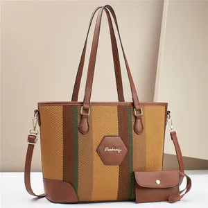Detail view of striped canvas tote bag with brown leather handles and matching small pouch