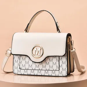 Close-up of cream crossbody bag with black M pattern and golden metal M logo