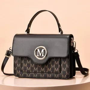 Detail of metal M logo on vintage brown monogram leather cross-body bag for women