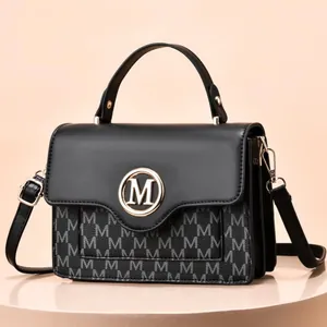 Detail of fashion crossbody bag with golden M logo, canvas print and accordion side layers