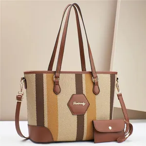 Detail of striped fabric tote bag with leather trim and gold metal logo charm