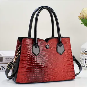 Detailed shot of red crocodile texture handbag with black handles and shoulder strap
