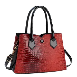 Elegant red crocodile textured handbag with black handles and adjustable shoulder strap
