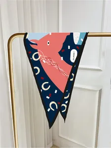 Detail of blue twilly silk scarf with coral horse patterns hanging on a golden rack