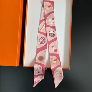 Pink silk twilly scarf with playful illustrations and elegant orange gift box