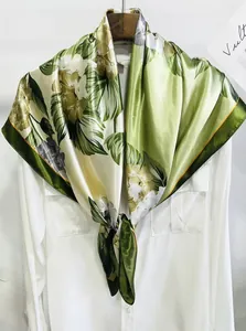 Détail des motifs de feuilles vertes tropicales sur un foulard en soie au reflet doux