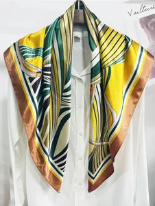 Close-up of a 90cm geometric striped silk scarf styled on a white shirt and wooden hanger