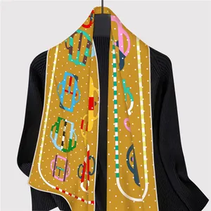 Detailed close-up of a French silk scarf featuring yellow horse-bit prints on black knitwear