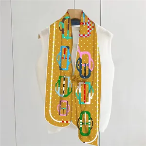 Detail of a ginger yellow silk scarf with white polka dots and harness patterns on a hanger