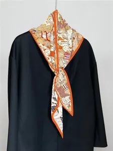Nahaufnahme eines Seidentuchs mit Kunstdruck und orangefarbenem Rand am Blazer