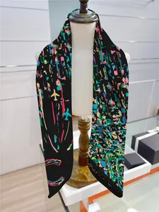 Detail view of a long black silk scarf with colorful graffiti patterns on a mannequin