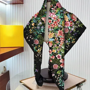 Elegant black silk scarf featuring vibrant floral prints on a mannequin display