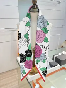 Dettaglio di un foulard in seta con motivi floreali e bordo rosso a contrasto sul busto