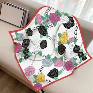 Foulard di seta 90cm con stampa di camelie e bordo rosso su un divano color crema
