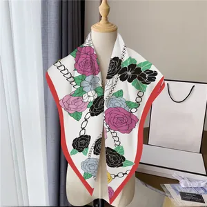 Dettaglio di sciarpa in seta con rose e catene con bordo rosso su manichino