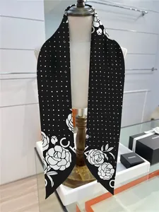 Dettaglio di un foulard in seta con motivo a camelia bianco e nero e logo del marchio
