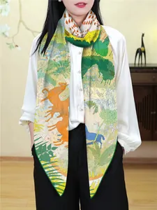 Detail eines eleganten Seidenschals mit Tierprint und Waldmotiven in Grün und Orange