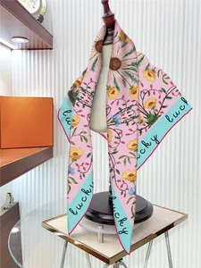 Close-up of pink silk scarf with sunflower print and blue hem tied on a wooden mannequin