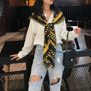 Détail d'un foulard français peint à la main porté en châle avec chemise blanche et jean