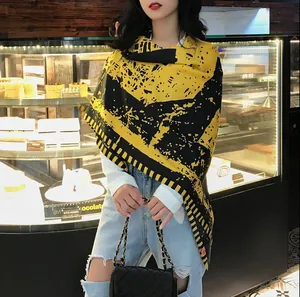 Détail d'un grand châle à motifs jaunes et noirs porté avec une tenue décontractée au café