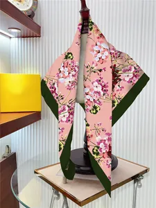 Detail of silk-like square scarf with pink floral patterns draped on a mannequin