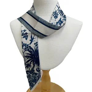 Navy and beige skinny scarf with vintage palm patterns on a white neck display stand