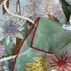 Close-up of georgette silk scarf with floral lily pattern and elegant pearl necklace