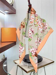 Detailed texture of floral silk scarf with apricot base and orange rolled edges on display