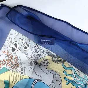 Detail of 100% silk georgette scarf showing fine ocean world print and blue hem texture