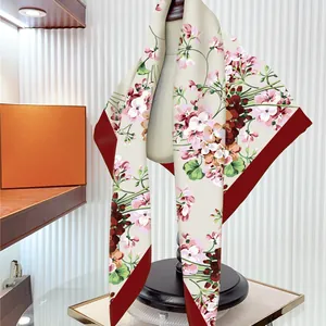 Elegant geranium floral print silk twill scarf with burgundy border draped on a model